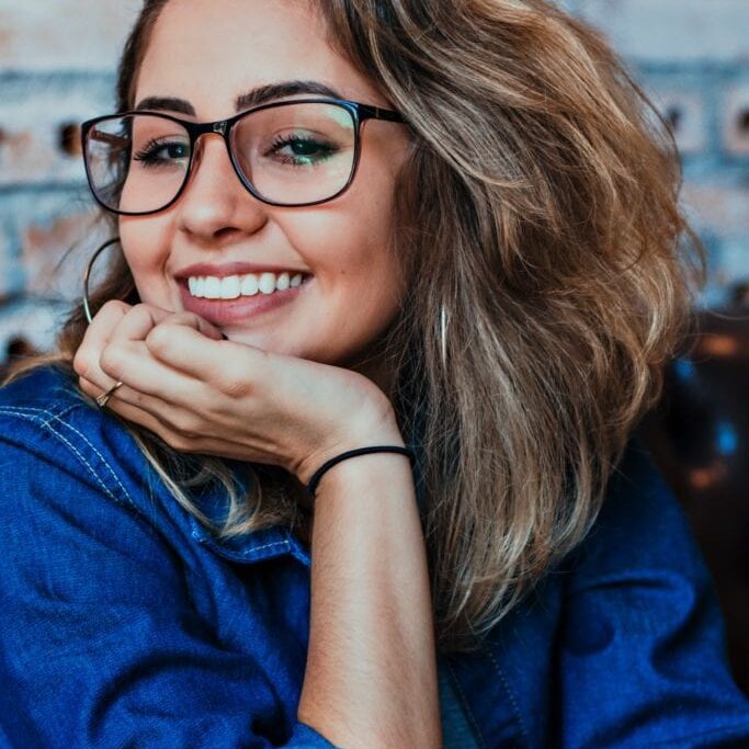 smiling woman in denim top and glasses